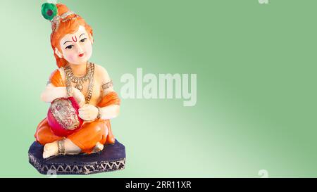 Hindu God Krishna on green background. Hindu God Kanha in childhood porcelain statuette isolate Stock Photo