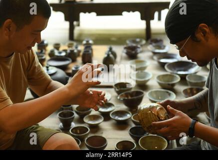 200904 -- HANGZHOU, Sept. 4, 2020 -- Yu YuanfengL introduces his pottery works to another pottery craftsman Wang Jueliang in Yu s studio in Hangzhou, east China s Zhejiang Province, Sept. 1, 2020. Yu Yuanfeng, a master degree graduate in ceramic art of China Academy of Art, is fascinated by making coffee in different forms of pottery. He resigned from a university after working as a teacher for 11 years and set up a studio in the outskirts of Hangzhou to make various types of pottery to brew coffee.  CHINA-ZHEJIANG-COFFEE-POTTERYCN WengxXinyang PUBLICATIONxNOTxINxCHN Stock Photo