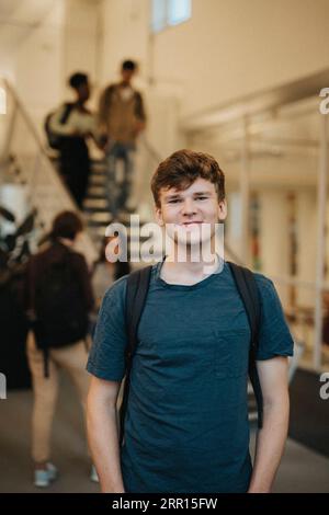 Portrait of smiling young male student standing in university Stock Photo