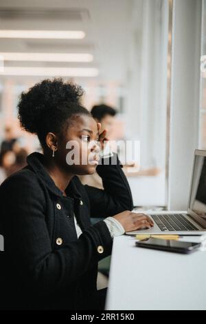 Serious female student studying on laptop in university Stock Photo
