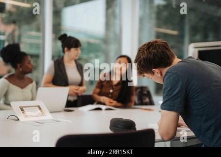 Young male student studying at table in university Stock Photo