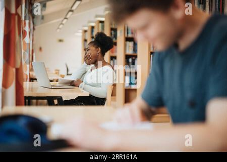 Student yawning while studying in library at university Stock Photo