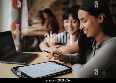 Smiling female students discussing over book at library Stock Photo