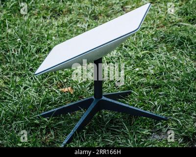 Germany - Aug 12, 2023: Side view of a rain-drenched Starlink internet antenna in the backyard, owned by SpaceX's Elon Musk. Stock Photo