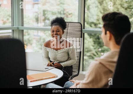 Cheerful student with laptop at table in university Stock Photo