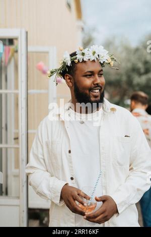 Smiling young man looking away while holding wineglass during dinner party at cafe Stock Photo