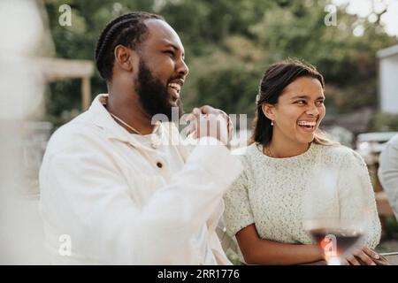 Happy male and female friends laughing during dinner party at cafe Stock Photo