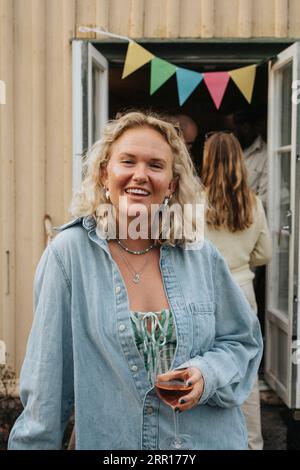 Portrait of smiling young woman holding wineglass during dinner party at cafe Stock Photo