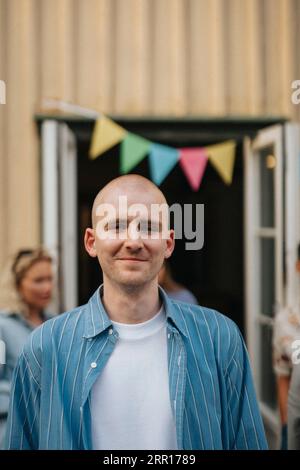 Portrait of smiling young man with shaved head during dinner party at cafe Stock Photo