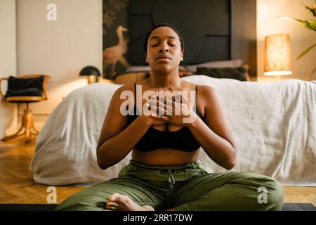 Woman meditating on exercise mat in bedroom at home Stock Photo