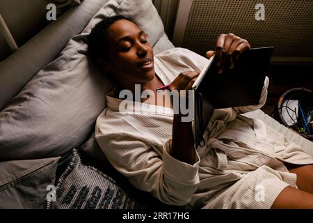 High angle view of woman writing in book while lying on bed at home Stock Photo