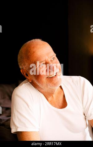 Happy thoughtful senior man sitting at home Stock Photo