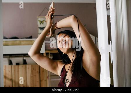 Carefree woman enjoying music through earphones at home Stock Photo