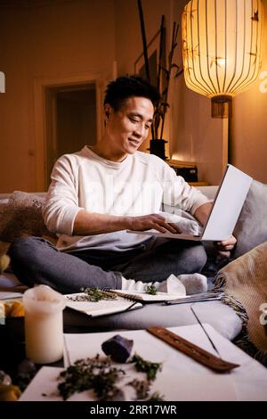 Smiling man using laptop while sitting on sofa in apartment Stock Photo