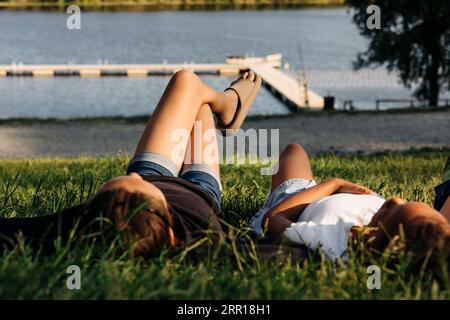 Female friends lying together on grass at summer camp Stock Photo