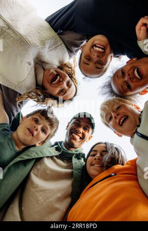 Directly below shot of kids huddling with counselors against sky Stock Photo