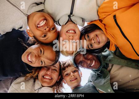 Directly below shot of children huddling with counselors Stock Photo