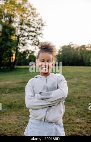 Portrait of smiling girl standing with arms crossed in playground Stock Photo