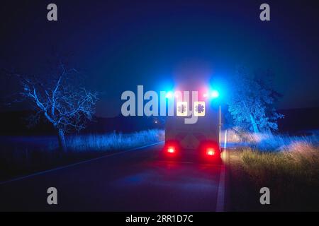 Ambulance car of emergency medical service on road at night. Themes rescue, urgency and health care. Stock Photo