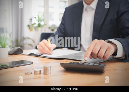 Man planning home budget and using calculator. Financial data analyzing counting on wood desk Stock Photo