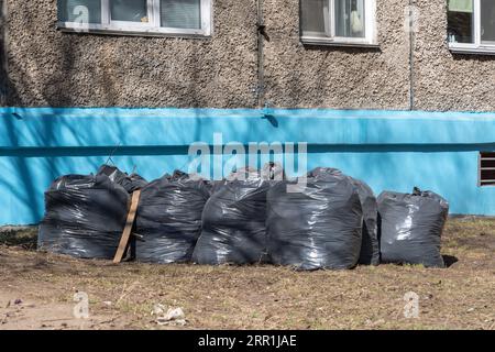 https://l450v.alamy.com/450v/2rr1jae/black-plastic-bags-full-of-spring-garbage-standing-along-the-blue-wall-of-the-house-spring-cleaning-the-concept-of-garbage-collection-ecology-envi-2rr1jae.jpg