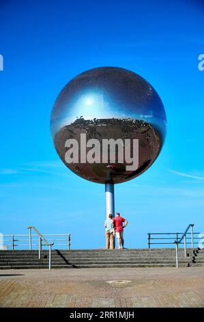 Couple stood infront of the Mirror Ball entitled They shoot horses don't they, onBlackpool seafront Stock Photo