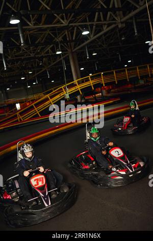 group of multiethnic people driving go kart on indoor circuit, speed racing and competition Stock Photo