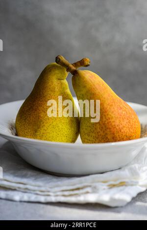 White marble plate with fresh juicy pears placed on a concrete table Stock Photo