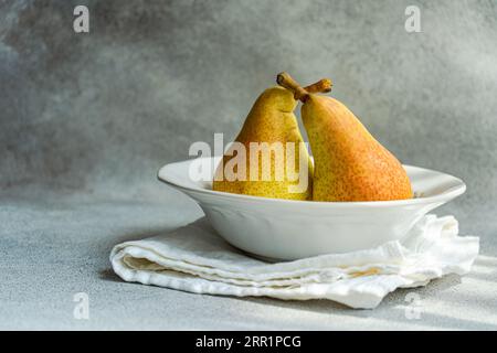 White marble plate with fresh juicy pears placed on a concrete table Stock Photo