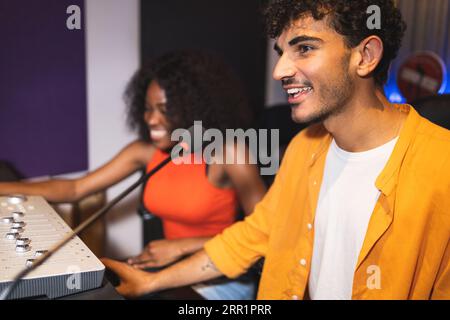 Male audio engineer and optimistic female African American singer creating hit song while using mixing board and computer software in musical studio Stock Photo