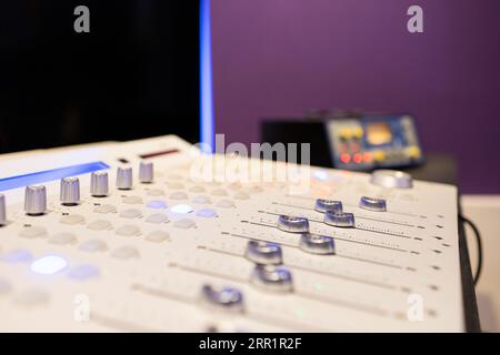 Mixing digital audio workstation controller with knobs channel strip display bus compressor plug ins placed in studio lights against blurred wall Stock Photo