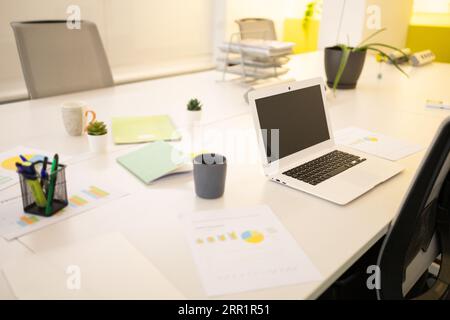 Netbook placed on white desk with papers and cup of hot drink in modern workspace Stock Photo