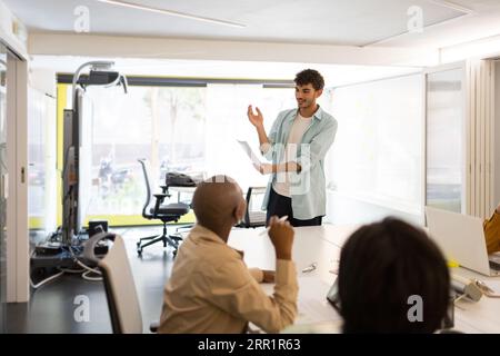Group of multiracial employees gathering together while working at project at white desk in modern office Stock Photo