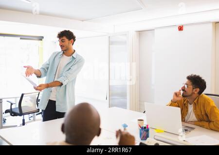 Group of multiracial employees gathering together while working at project at white desk in modern office Stock Photo