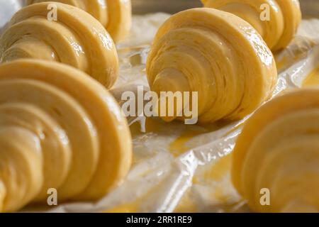 Sets of delicious raw croissant with creamy butter on table with white polythene cover in bakery Stock Photo