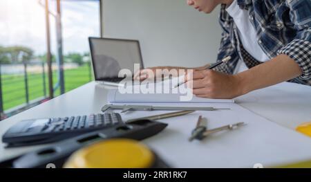 Close up of male engineer asian working on blueprint architectural project at construction site at desk in office Stock Photo