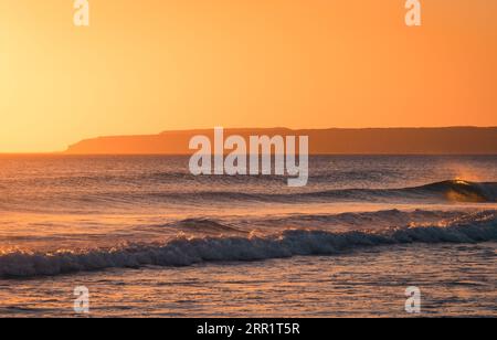 Breathtaking view of vibrant sundown sky over wavy sea in evening Stock Photo
