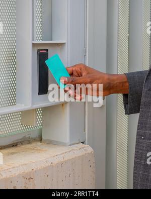 Side view of body part of crop unrecognizable African American male entrepreneur in formal suit using security access ID card for opening doorway Stock Photo
