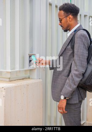 Side view of African American male entrepreneur in formal suit using security access ID card for opening doorway Stock Photo