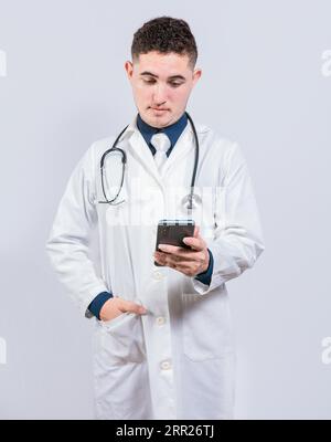 Handsome doctor using phone on isolated background. Young latin doctor holding telephone isolated Stock Photo