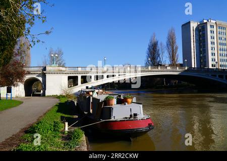 Barge moored next to north bank of the River Thames, Reading Bridge and Reading Bridge House office block (R), Caversham, Berkshire, England Stock Photo