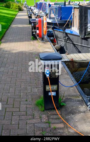 Shoreline charging bollards located in a marina on the canal system in Cheshire, UK used to connect narrowboats to a power supply. Stock Photo