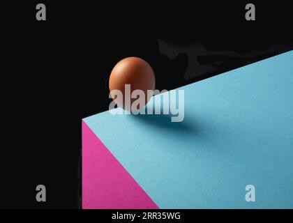 A still life image of an egg balancing on the edge of a drop off Stock Photo