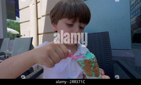 Small boy indulging himself with colorful ice-cream cone during sunny ...