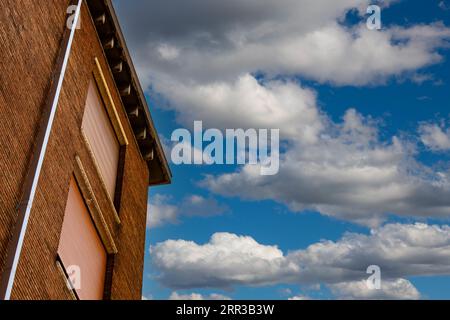 A condominium building stands tall against the backdrop of Parma's blue sky adorned with fluffy white clouds Stock Photo
