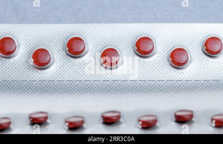 Red tablets in blister pack, silver aluminium foil pack for capsule and tablets pills in pharmaceutical industry. Stock Photo