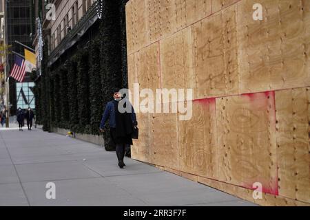 201101 -- NEW YORK, Nov. 1, 2020 -- A woman walks past a boarded up store on the Fifth Avenue in New York, the United States, on Nov. 1, 2020. The moves come as retailers are trying to protect themselves against looting or other civil unrest in the coming days.  U.S.-NEW YORK-STORES-BOARDING UP WangxYing PUBLICATIONxNOTxINxCHN Stock Photo
