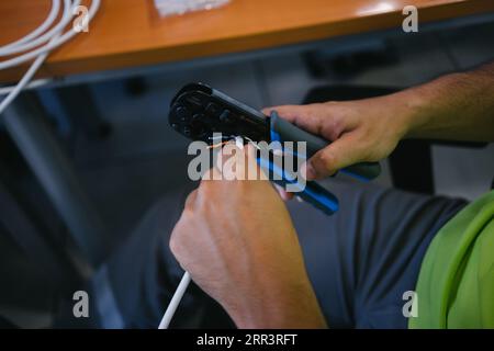 Unrecognizable hand cutting ethernet network cable with tool for crimping rj-45 connectors. Stock Photo