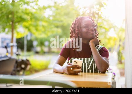 Portrait of a black non-binary person sitting in an outdoor cafe Stock Photo