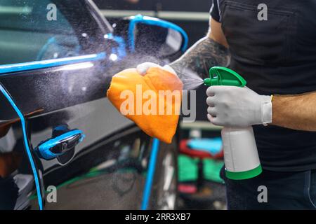 Car detailing studio. Man sawing cleaner on a rag Stock Photo